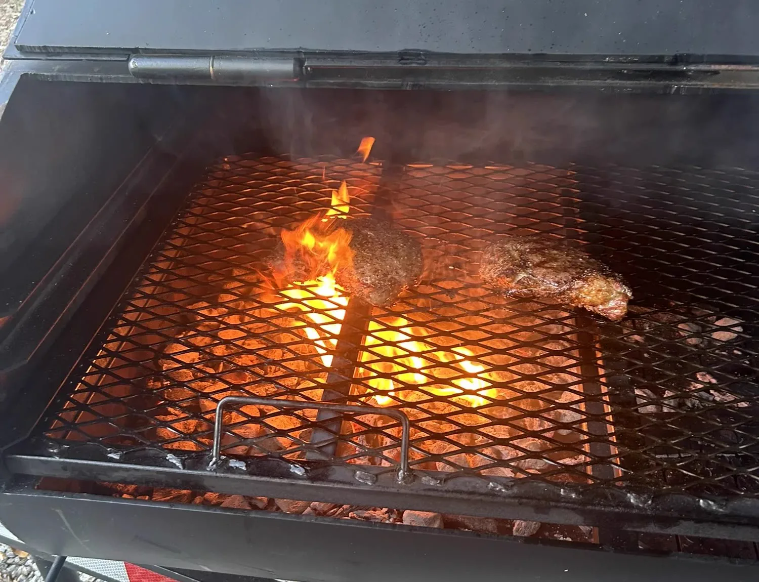 Pit beef searing over an open flame on the smoker